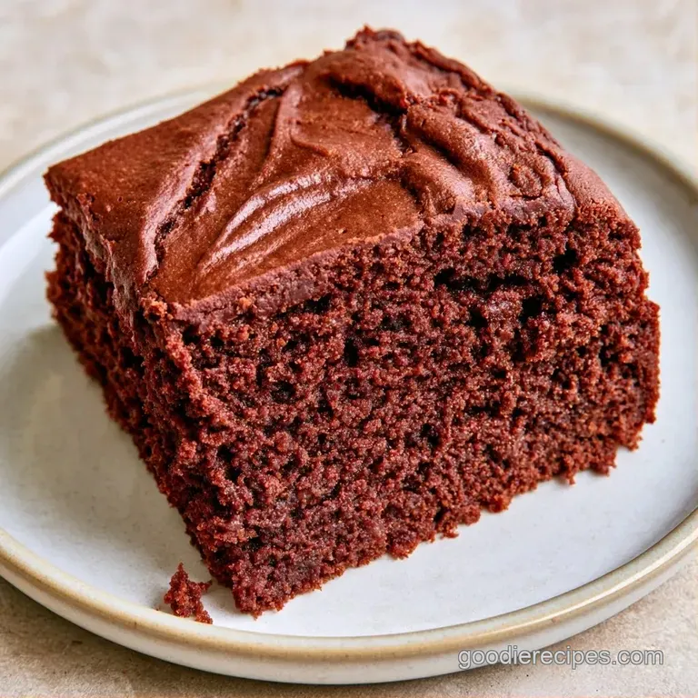 A slice of deep cocoa cake on a white porcelain plate, garnished with a swirl of cream and fresh red berries.