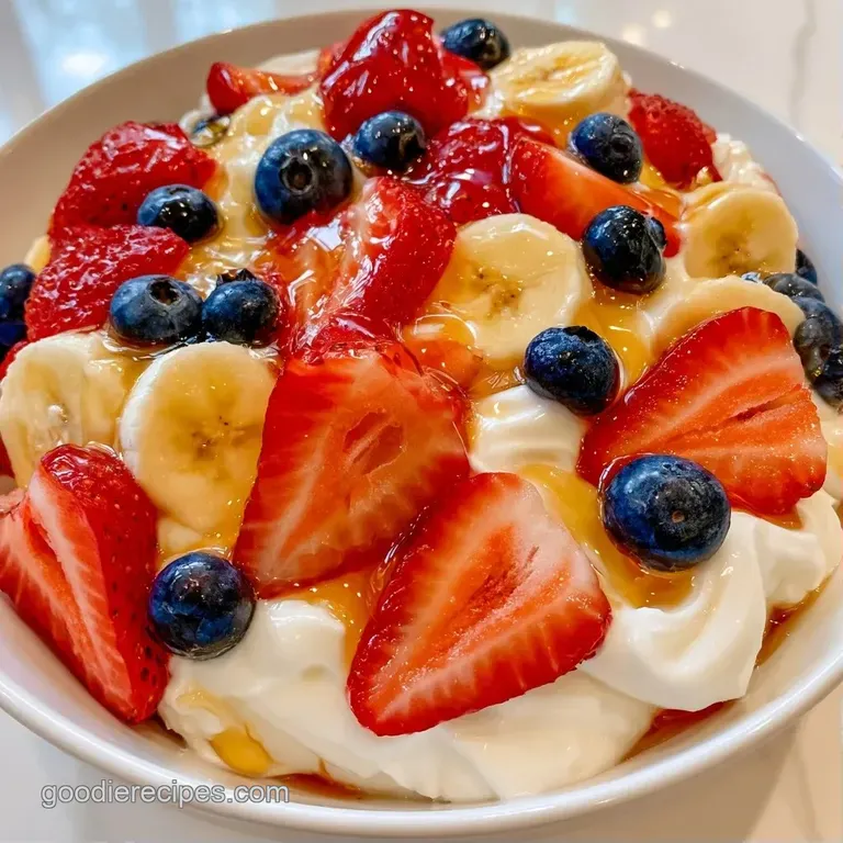 Elegant white bowl with swirls of thick yogurt, colorful tropical fruit slices, and a sprinkle of toasted almonds.
