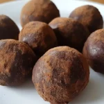 Close-up of no sugar, no flour energy bites stacked on a wooden board, showing their chewy texture and natural ingredients like oats and chocolate chips.